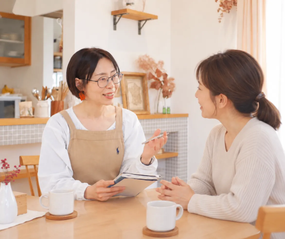 テーブルでお客様と話しながら、片づけの相談をしているいわたまきこ